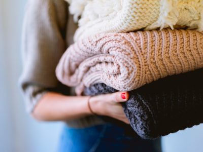 woman holding household items such as knitted blankets