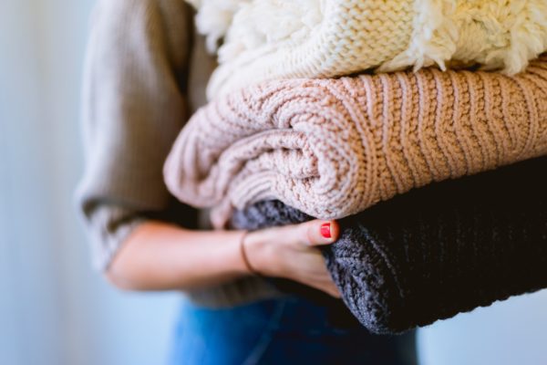 woman holding household items such as knitted blankets